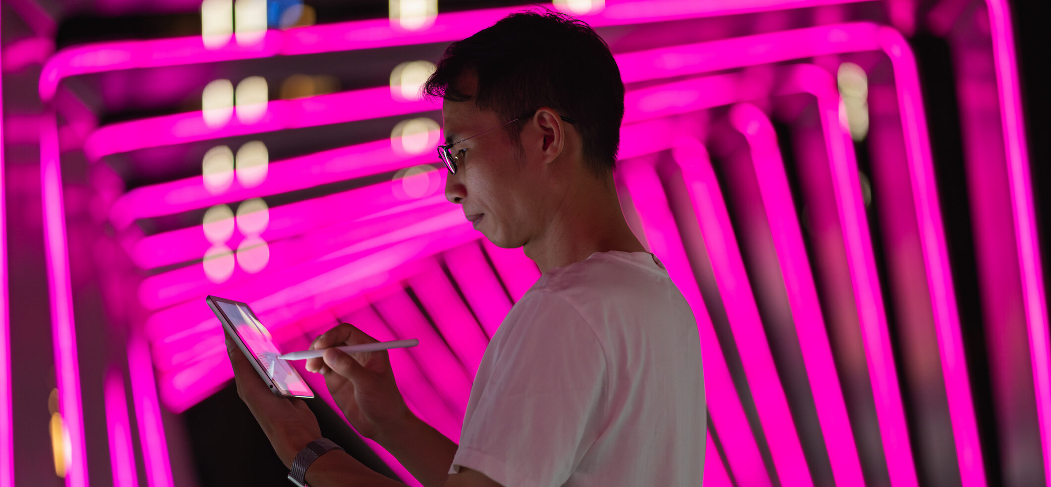 Man is using tablet on pink neon background