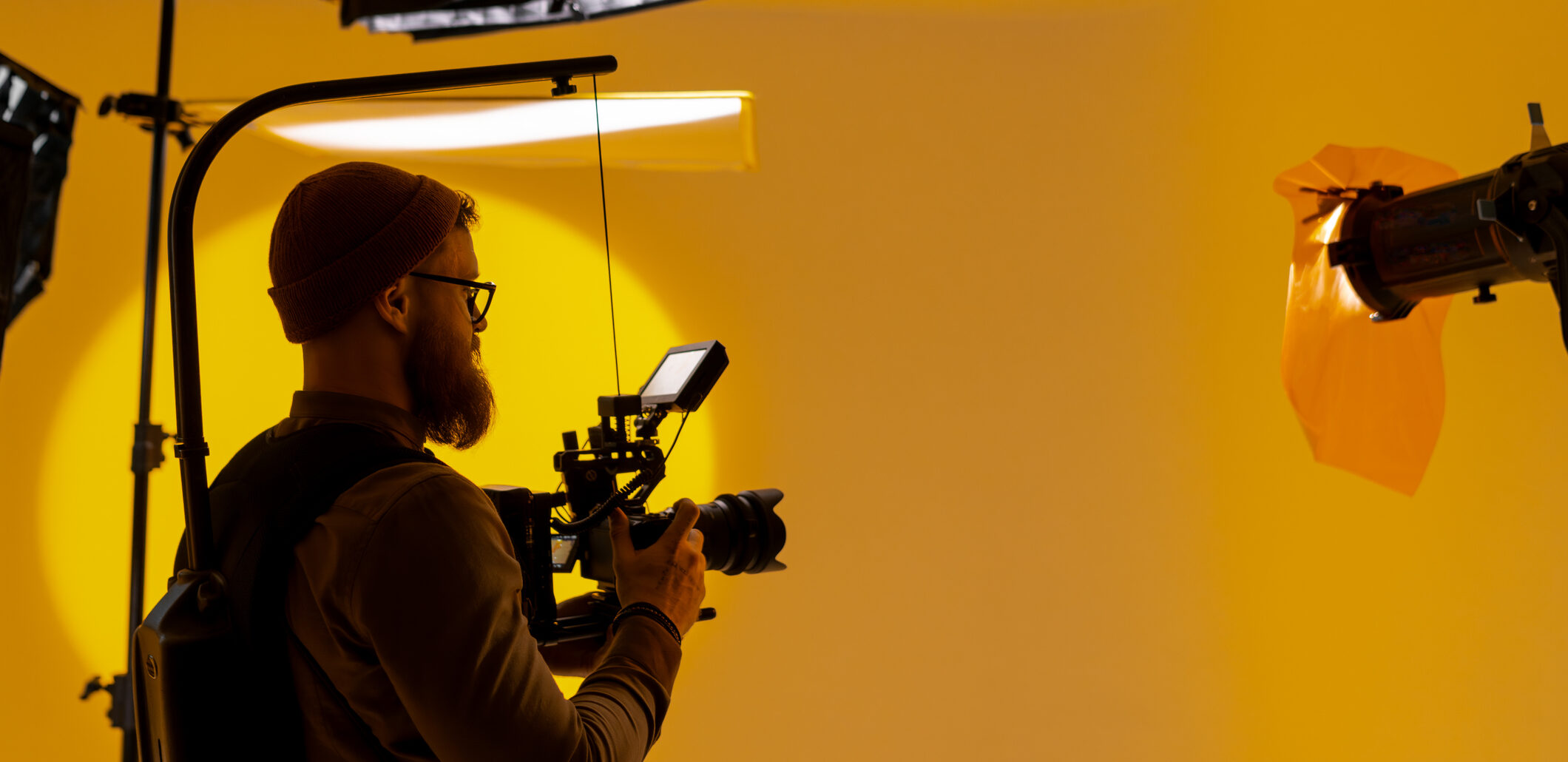 A videographer is capturing footage in a yellow room using a video camera, showcasing his talent in the film industry as a cinematographer. AVEC Tax Relief.